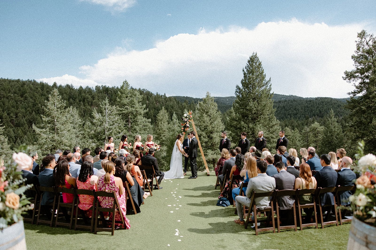 Woodlands Colorado is one of the best Colorado wedding venues near Denver. In this photo, a couple is sharing their vows in front of their friends and family during the ceremony.