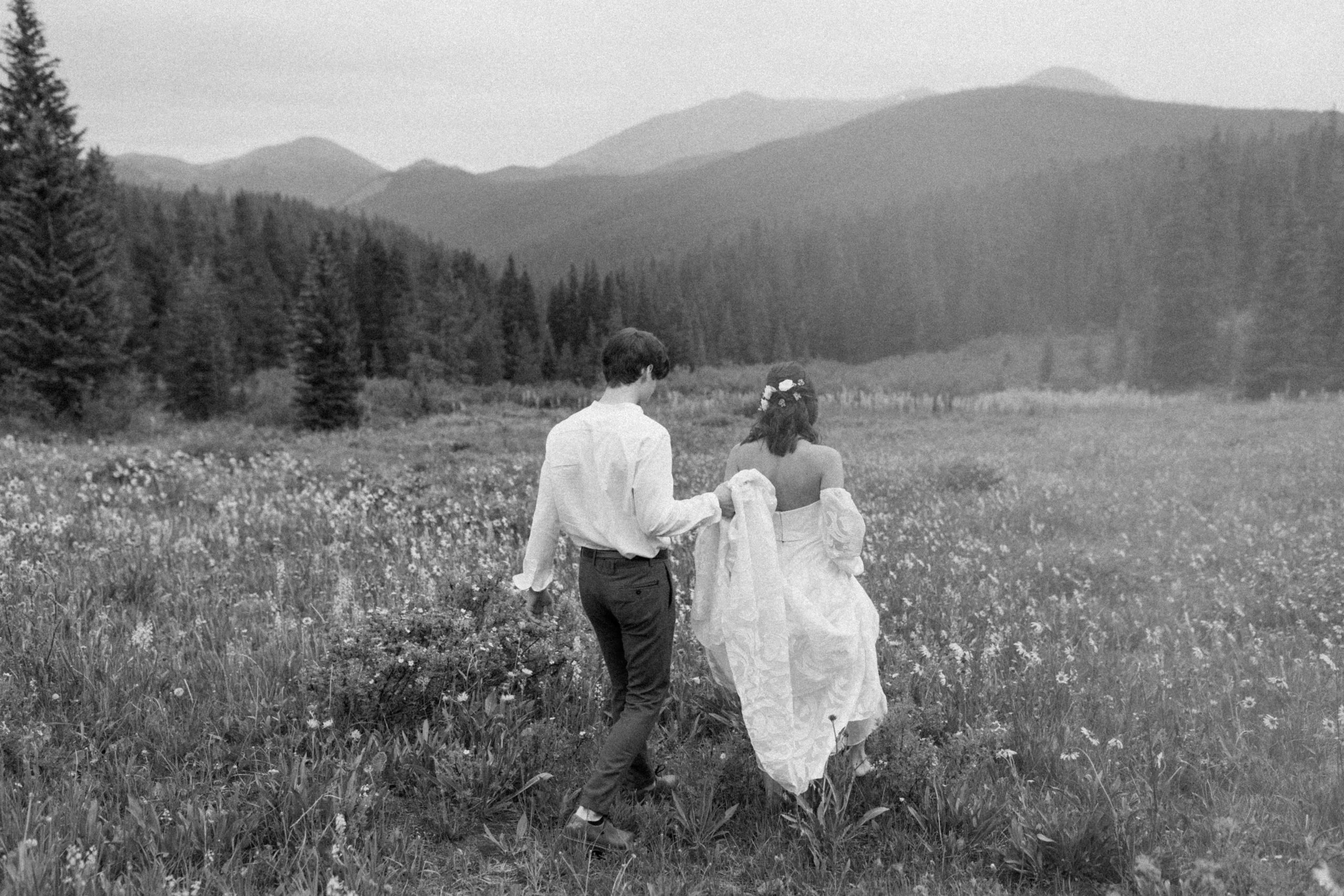 Couple walking through wild flowers after their elopement.