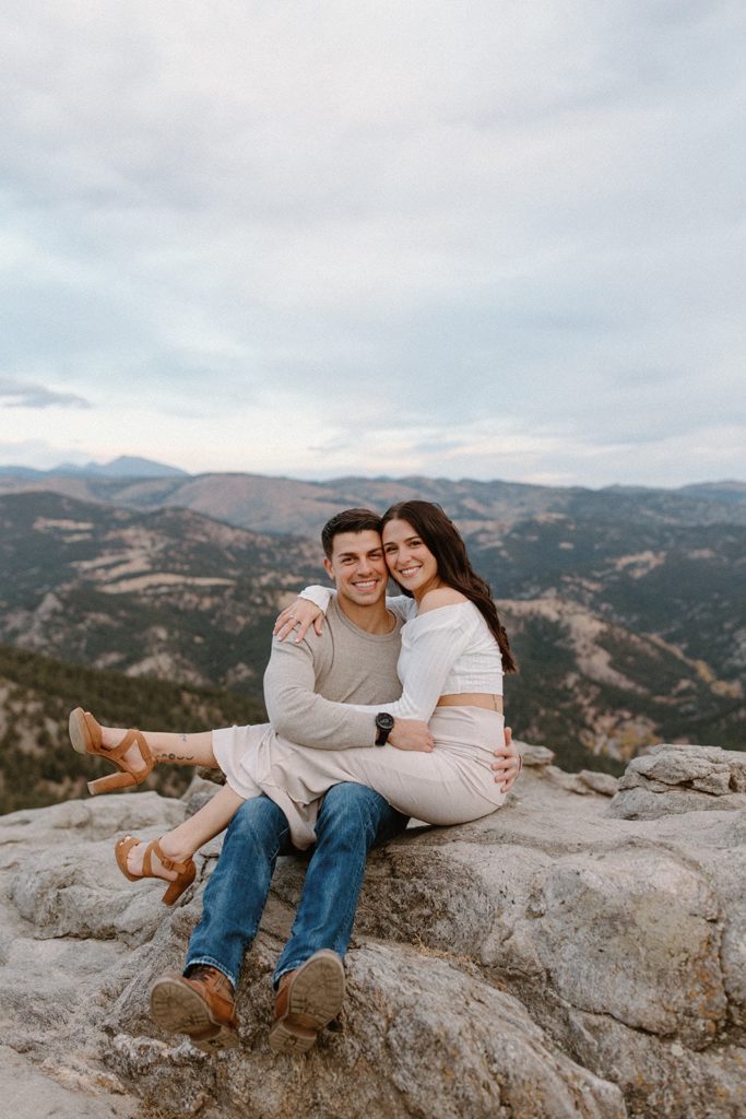 woman sitting on her man's lap at their Lost Gulch Overlook Sunrise Engagement Session