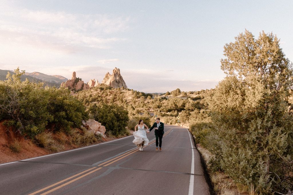 man and woman running on the road for their Garden of the Gods Elopement 