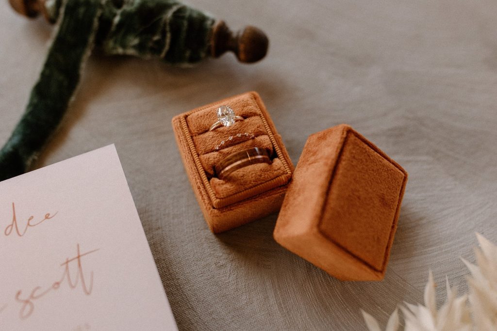 wedding and engagement rings in a orange velvet box for a North Star Gatherings Wedding