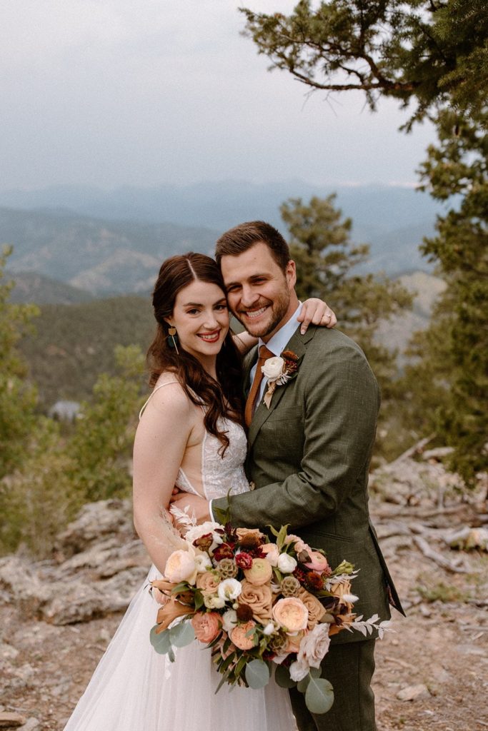 man and woman smiling at the camera on a mountain for their North Star Gatherings Wedding