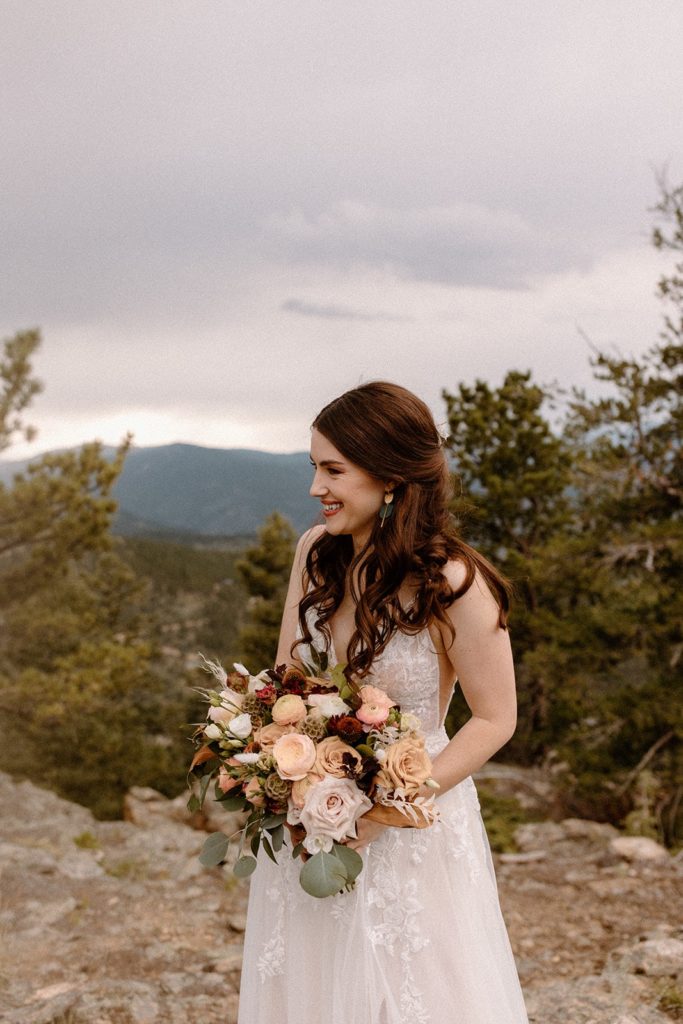 bride laughing on a mountain with her bouquet for her North Star Gatherings Wedding