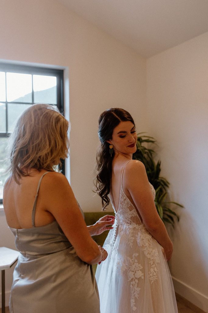 bride being buttoned into her dress on her North Star Gatherings Wedding day