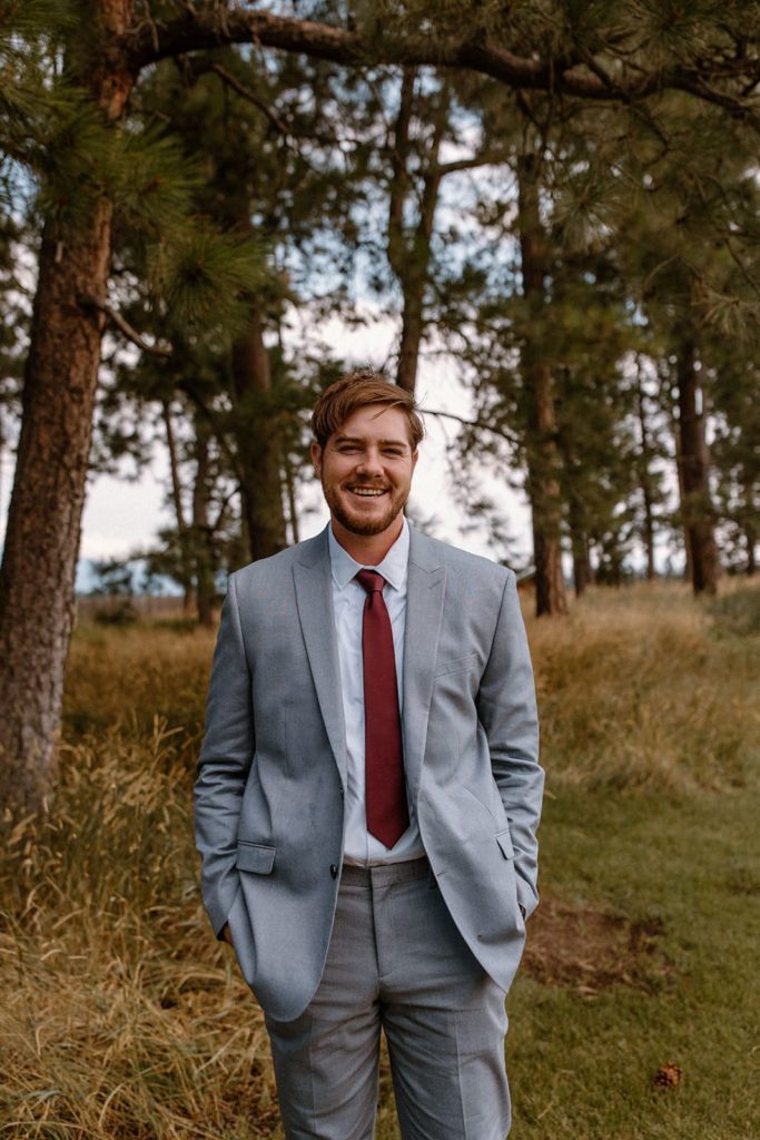 groom in a suit standing smiling before his Montana Elopement