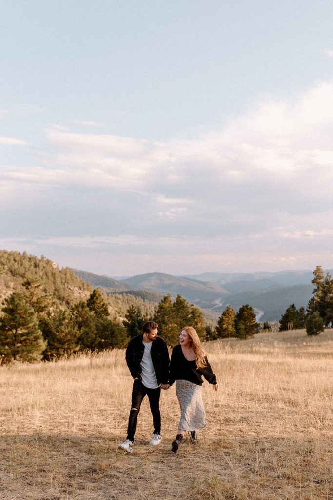 man and woman walking in a field for Mountain Engagement Photos