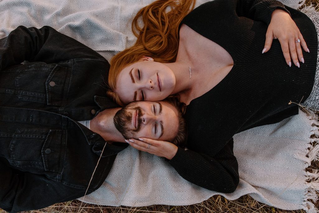 man and woman face to face lying on the ground for Mountain Engagement Photos
