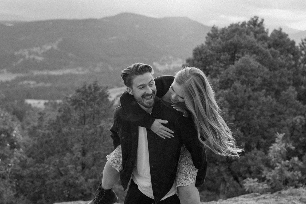 man giving woman a piggy back ride in Mount Falcon Park for Mountain Engagement Photos