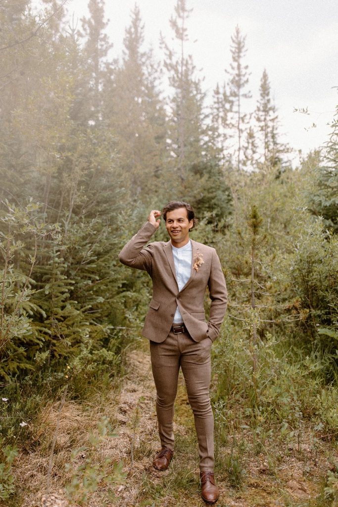 man in a suit standing in the woods on his Colorado elopement day