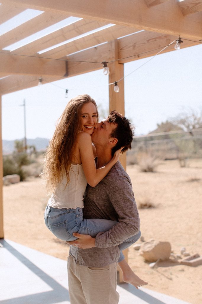 man holding woman and kissing her on the cheek in Joshua Tree National Park