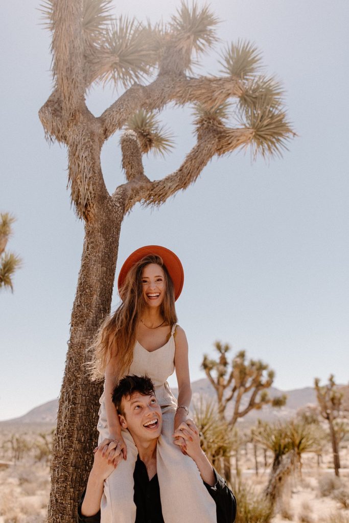 woman in a red hat on the shoulders of her boyfriend in Joshua Tree National Park