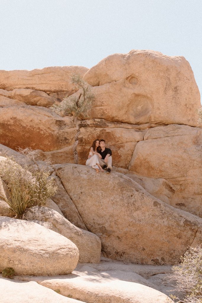 man and woman sitting on a big rock in Joshua Tree National Park
